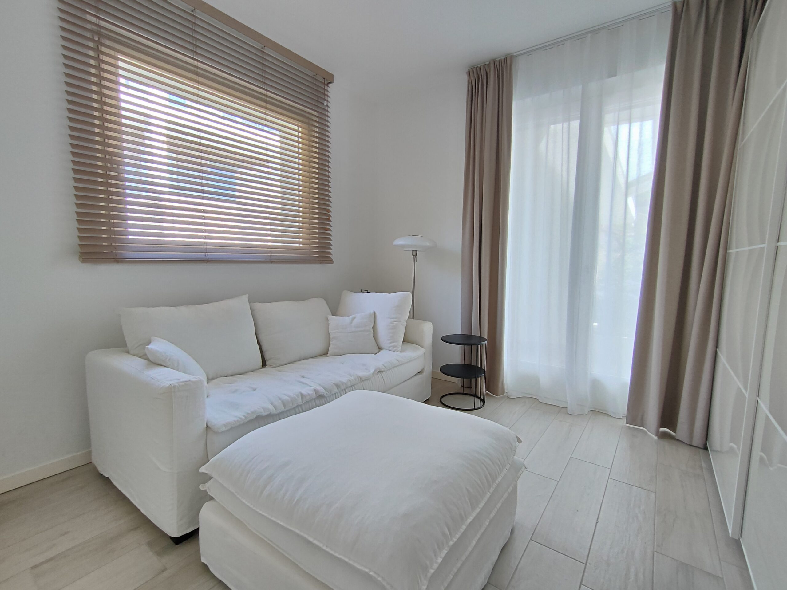 Elegant white living room in a Fabula Home Rental property with plush seating and chic decor, bathed in natural light