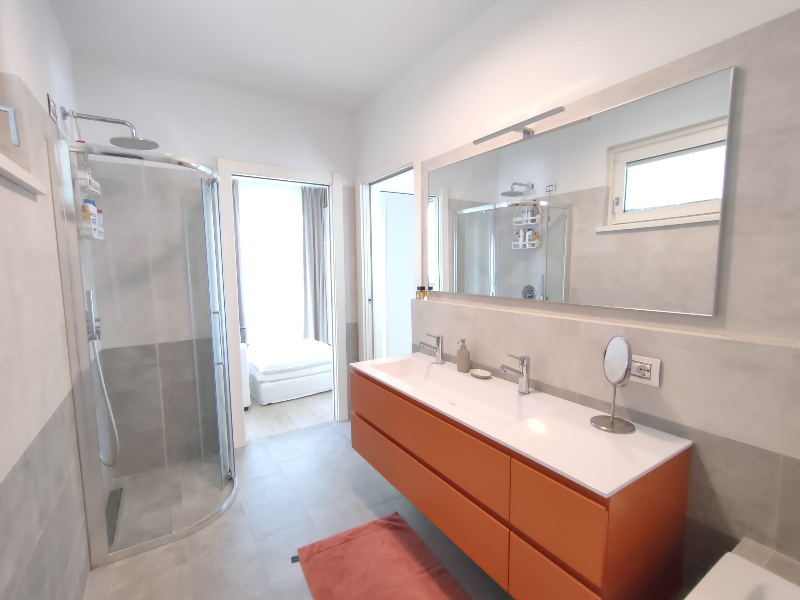 Sleek bathroom with a contemporary orange vanity and a spacious walk-in shower, reflecting modern elegance