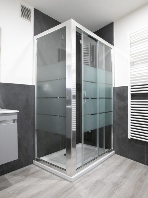 Sleek modern bathroom with glass shower enclosure and dark grey tiles in Lovere apartment