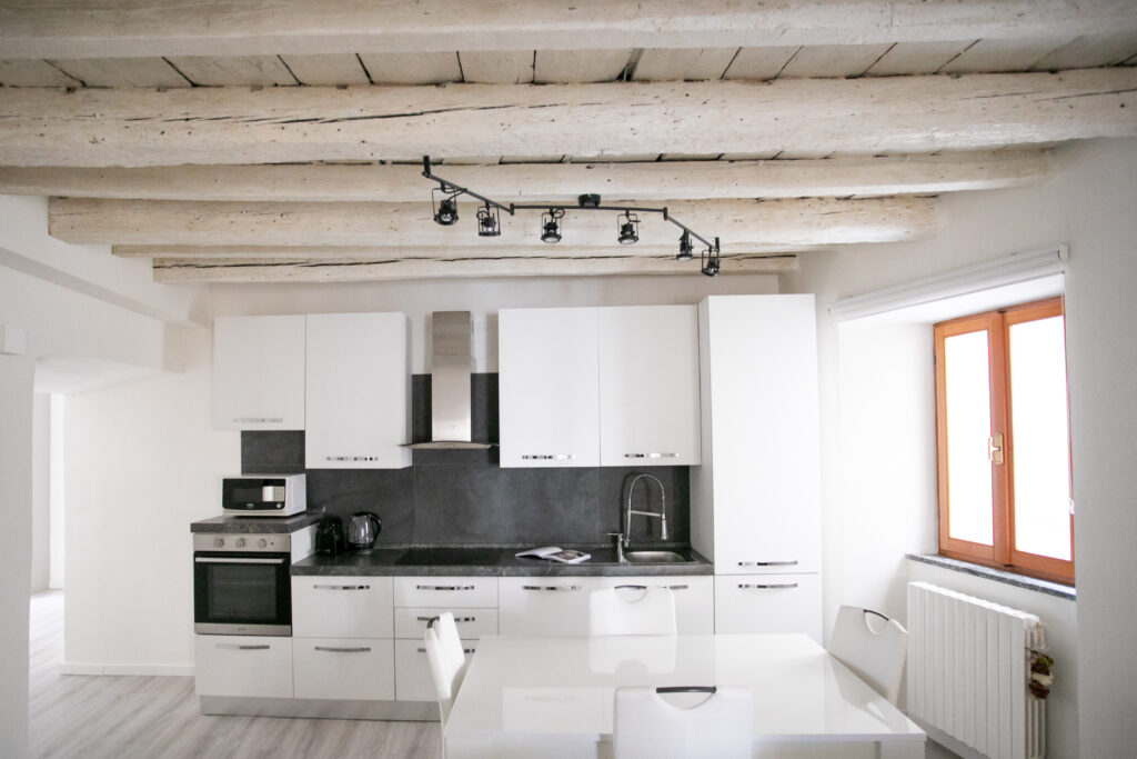 Spacious living room in Lovere apartment showcasing exposed wooden beams and modern furniture