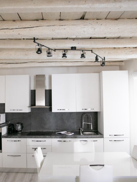 Spacious living room in Lovere apartment showcasing exposed wooden beams and modern furniture