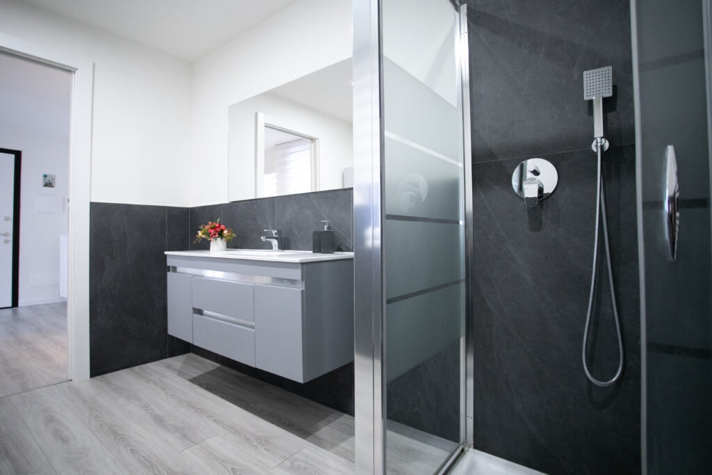 Modern bathroom with floral arrangement and grey tiles in Lovere's historic center apartment