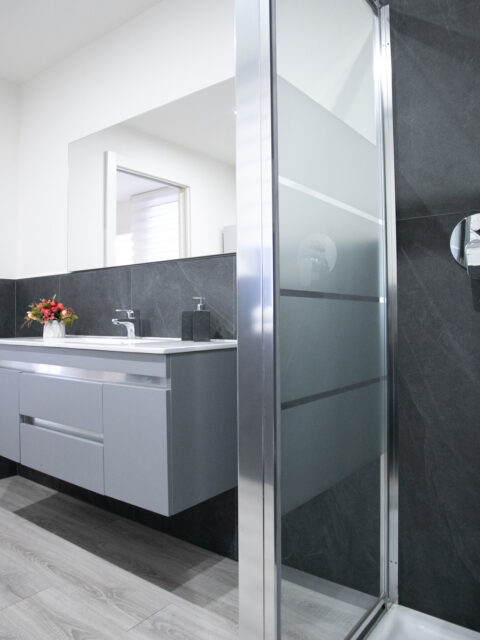 Modern bathroom with floral arrangement and grey tiles in Lovere's historic center apartment