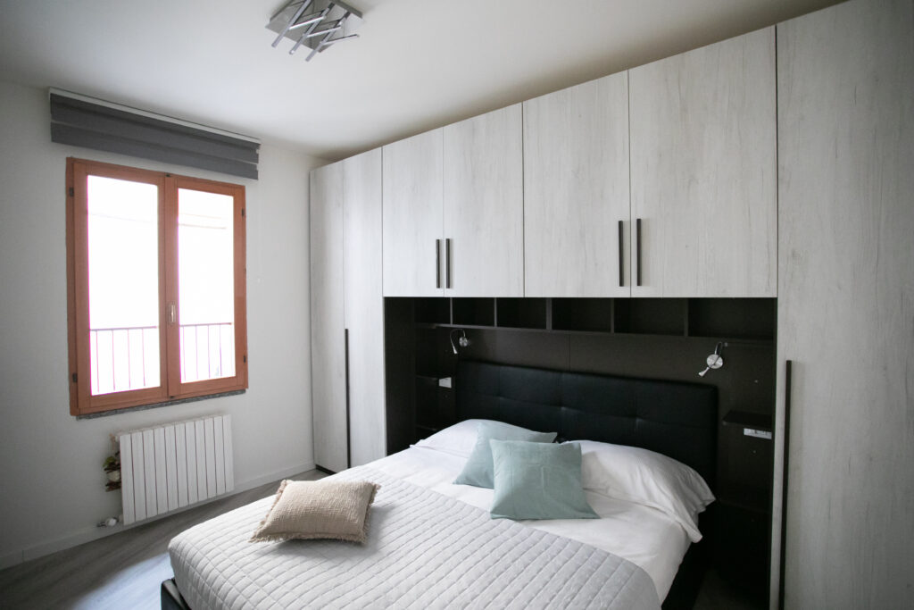 Modern bedroom in Lovere with a plush headboard and stylish overhead lighting