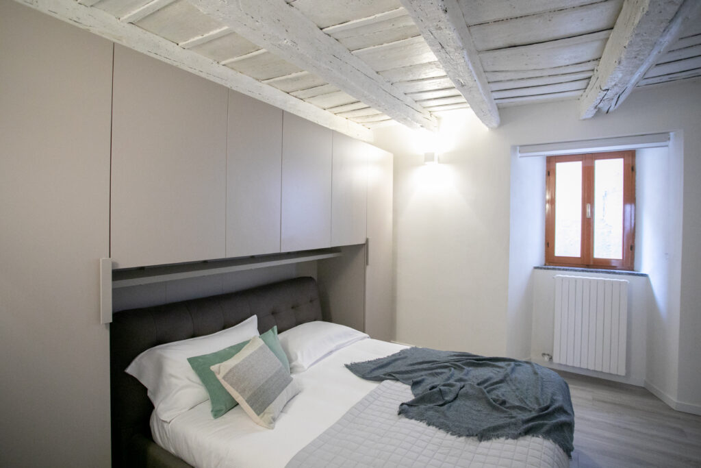 Cozy bedroom in Lovere with exposed wooden beams and minimalist decor