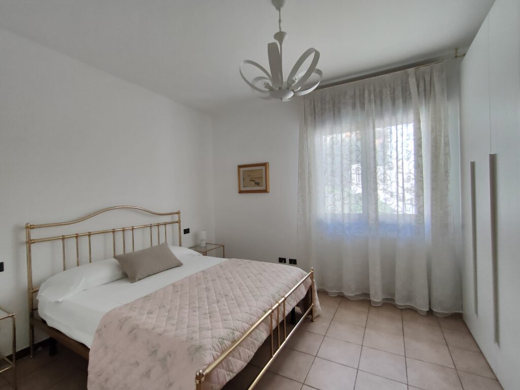 Inviting bedroom with a classic gold bed frame and airy curtains in GiannaRosa Apartment, Lovere