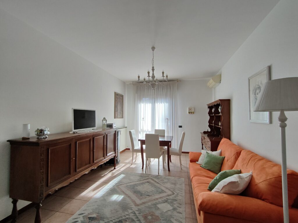 Spacious and well-lit living and dining area with plush orange sofa and classic decor in GiannaRosa Apartment, Lovere