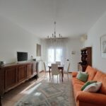 Spacious and well-lit living and dining area with plush orange sofa and classic decor in GiannaRosa Apartment, Lovere