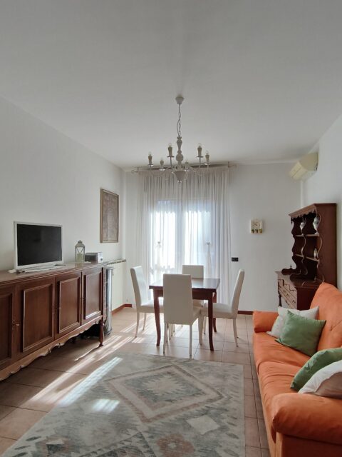 Spacious and well-lit living and dining area with plush orange sofa and classic decor in GiannaRosa Apartment, Lovere