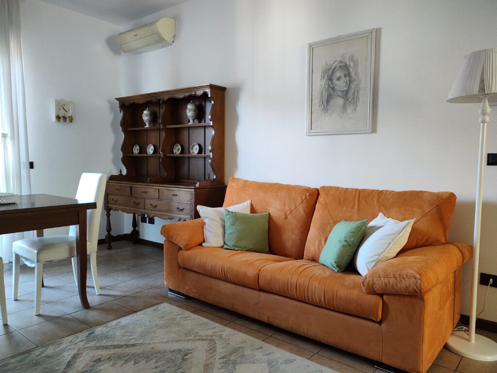 A cozy living room featuring an orange sofa and classic wooden furniture at GiannaRosa Apartment in Lovere