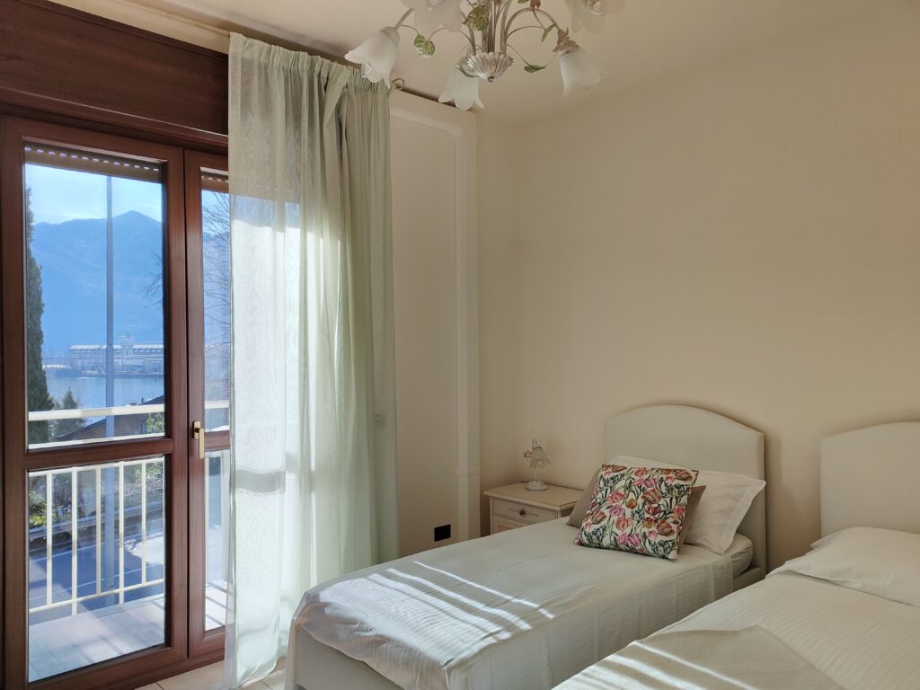 Sunlit twin bedroom with a picturesque view of Lovere's natural beauty at GiannaRosa Apartment