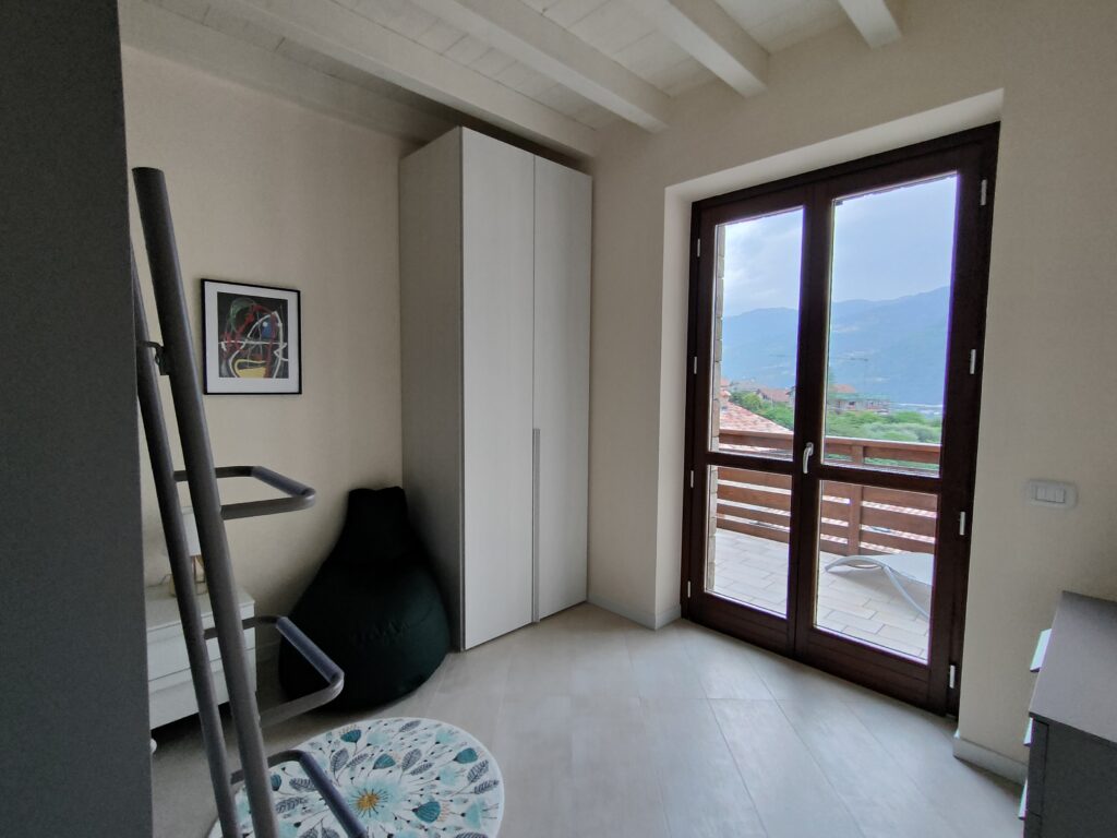 Bedroom with balcony offering scenic views at Fabula Home Rental near Lake Iseo