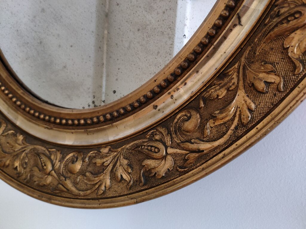 Close-up of an ornate golden frame with intricate leaf patterns, adding a touch of elegance to Lakeview Apartment's decor