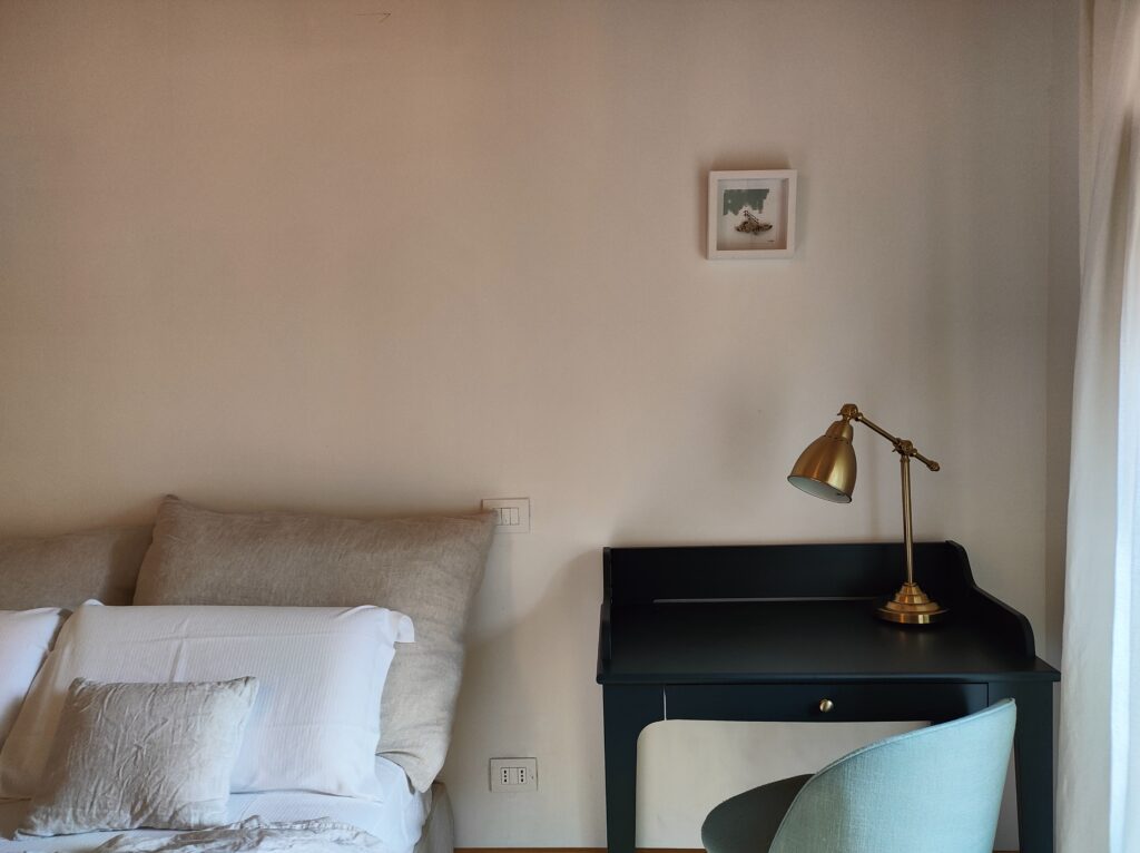 Stylish work corner in Lakeview Apartment with a sleek black desk and vintage gold lamp, complementing the tranquil bedroom atmosphere