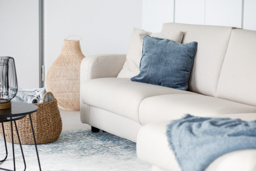 A contemporary living room at Seliera with a plush beige sofa and wicker details