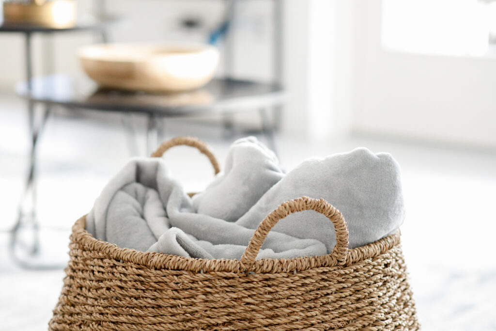 Soft linens in a natural woven basket against a modern backdrop at Seliera