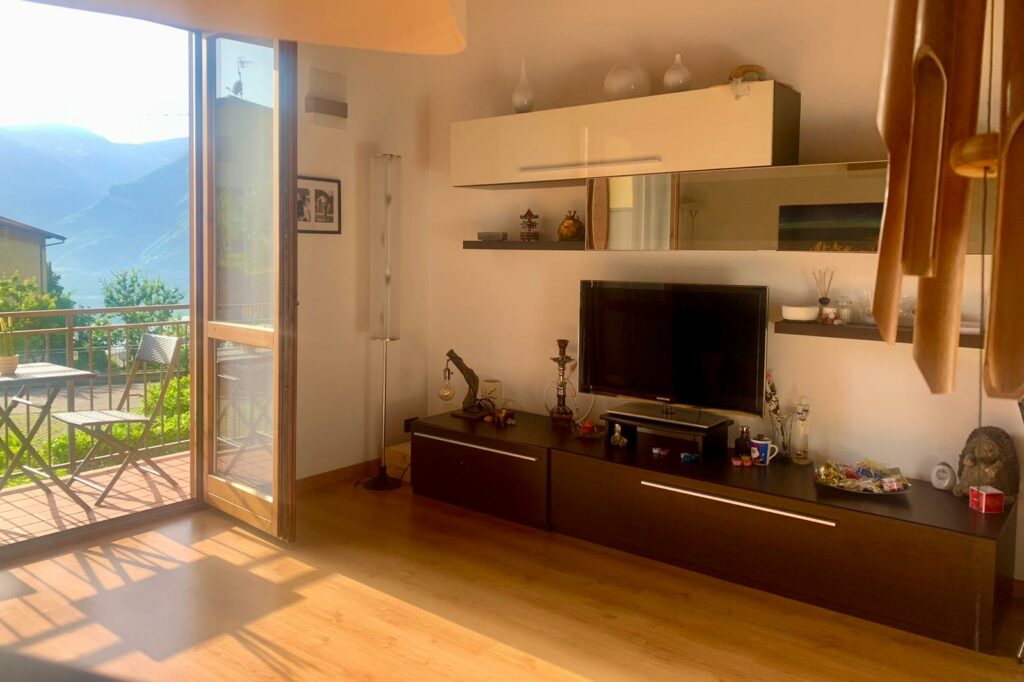 Sunlit living room with open balcony doors overlooking the mountains at La Rocca