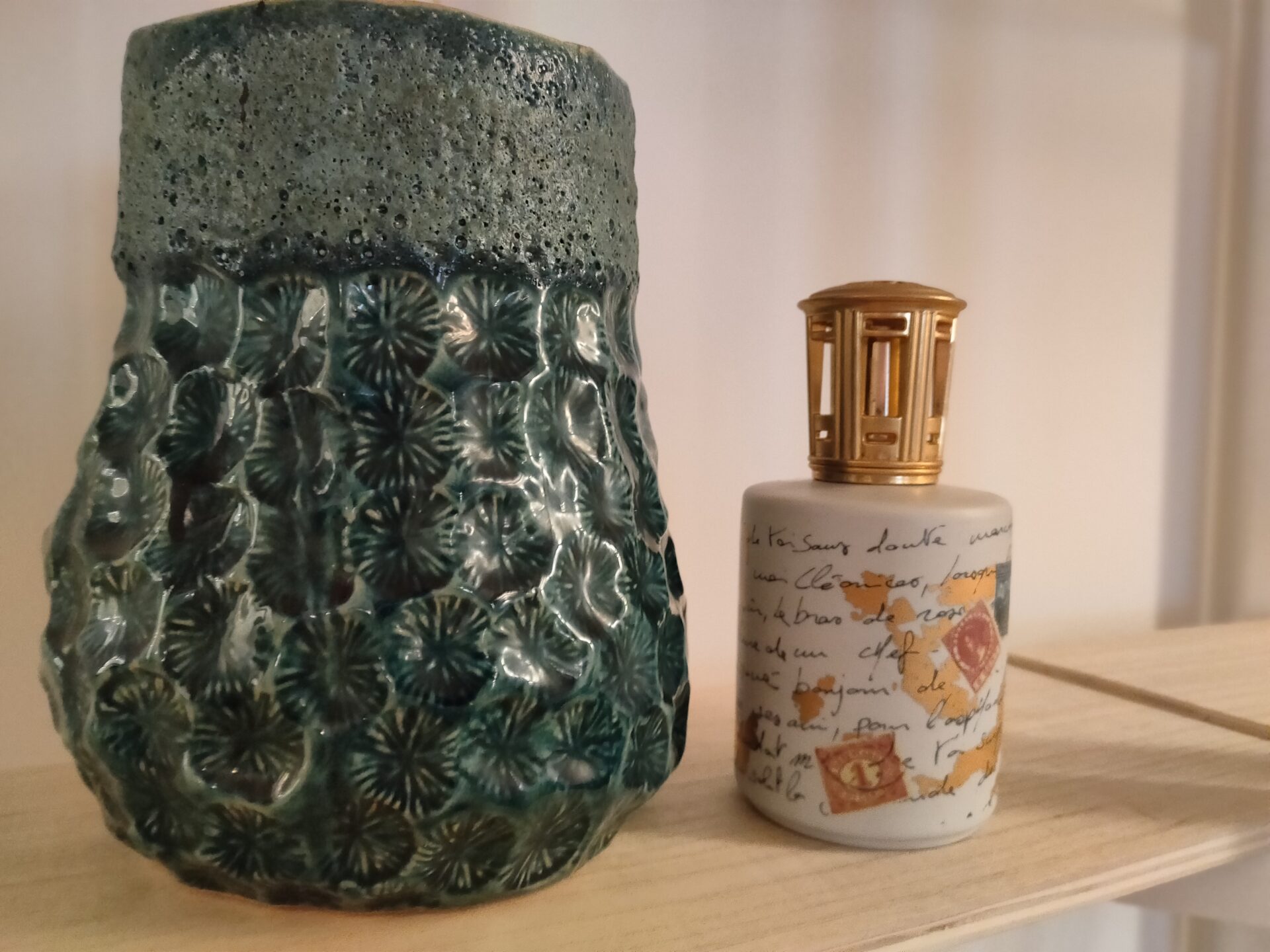 An intricate green artisanal vase next to a vintage-inspired perfume bottle on a Lakeview Apartment shelf