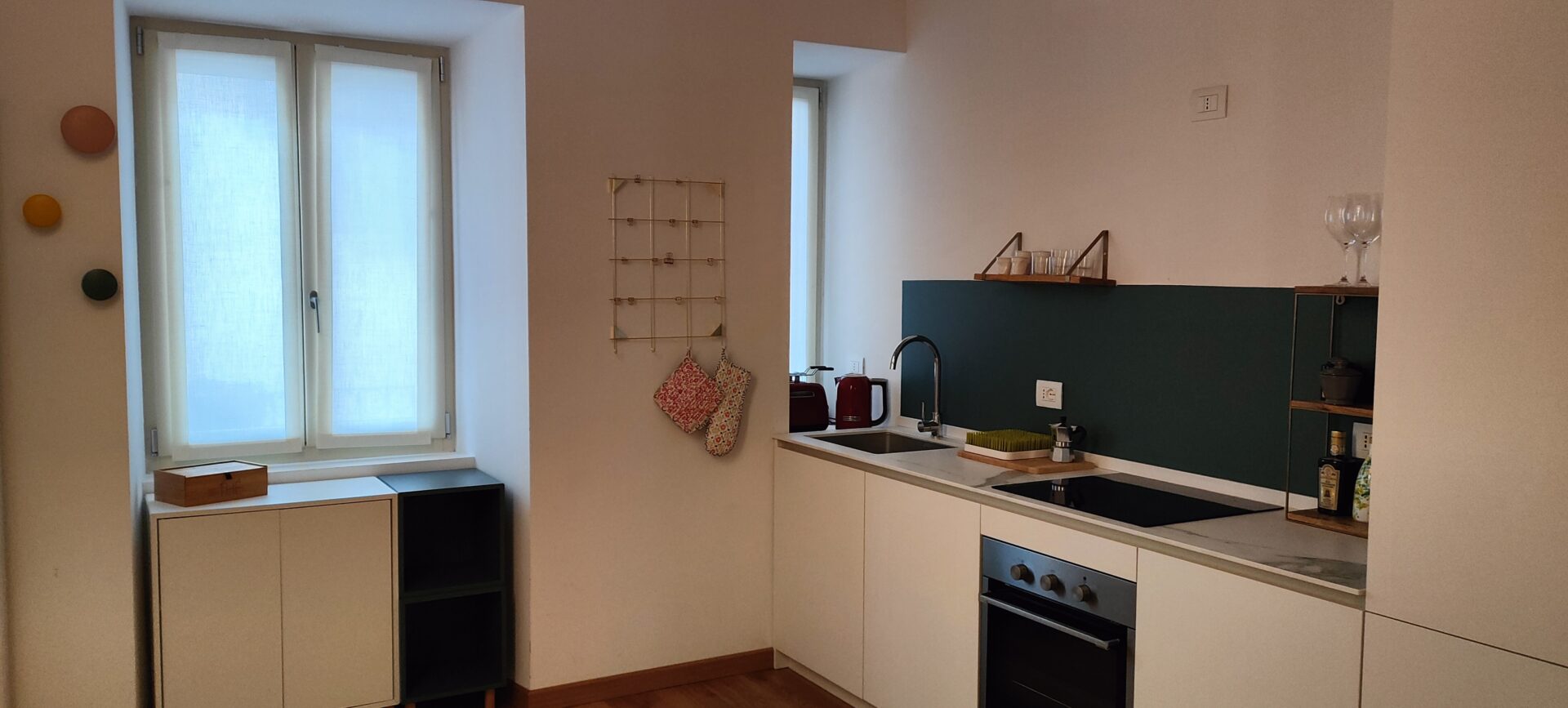 Lakeview Apartment's kitchenette combines modern white cabinets with a striking green backsplash, set in a bright and airy space