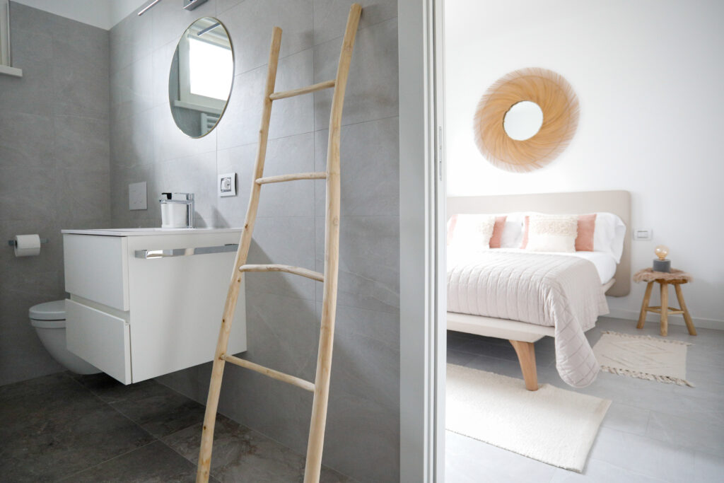 View of a sleek modern bathroom through a door at Seliera, with a bedroom glimpse