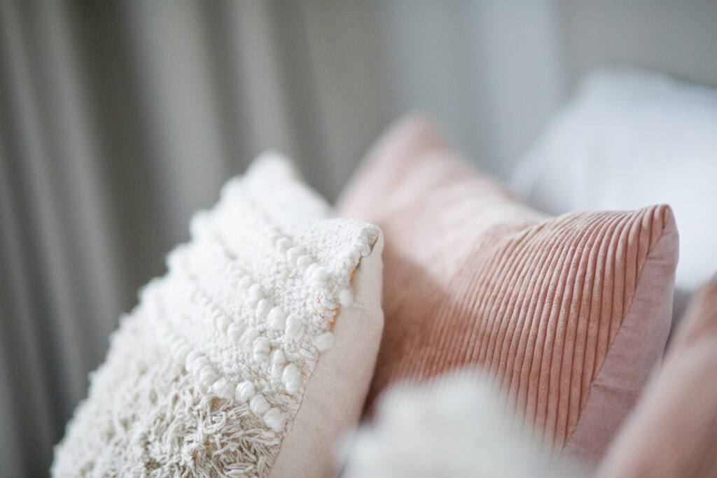 Close-up of textured and velvet throw pillows on a bed at Seliera