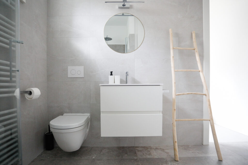 Elegant bathroom interior with gray tiling and a round mirror at Seliera