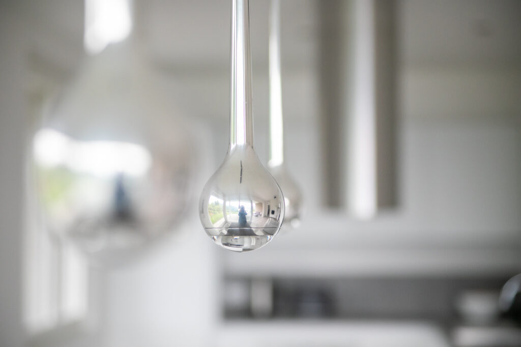 A trio of modern pendant lights hanging above with a soft-focus view of Lake Solto in the background