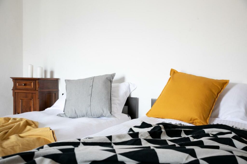 Chic bedroom with grey and mustard pillows and a geometric blanket at La Stallina Ground Floor