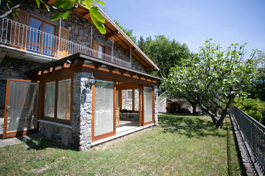 Exterior view of Villa Simone featuring the sunroom extension and well-kept garden with mountain scenery