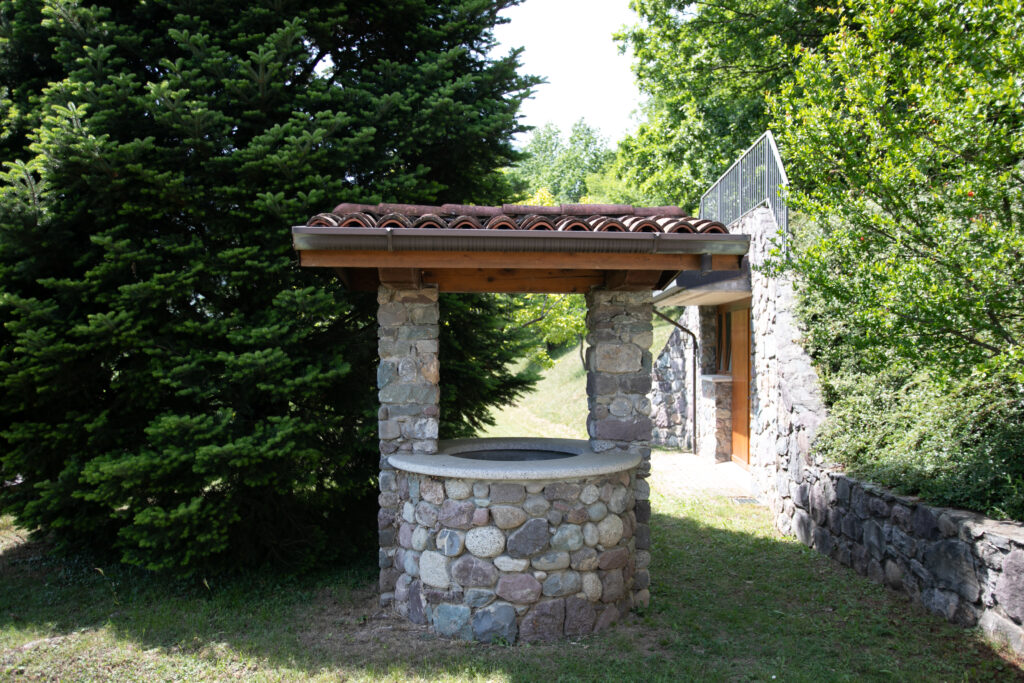 Traditional outdoor stone well and grill area in Villa Simone's verdant garden