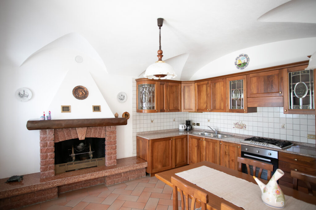 Traditional kitchen with brick fireplace and wooden cabinets in Villa Simone