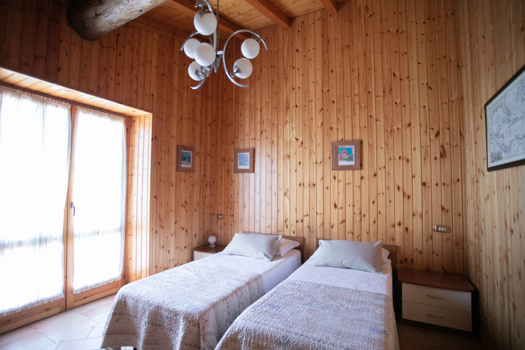 Cozy twin bedroom with pine walls and charming decor in Villa Simone