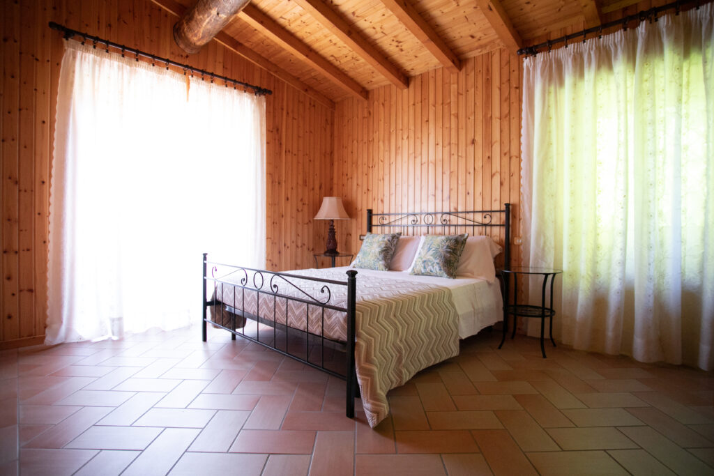 Bright and airy bedroom with large windows offering a view of the lush surroundings at Villa Simone