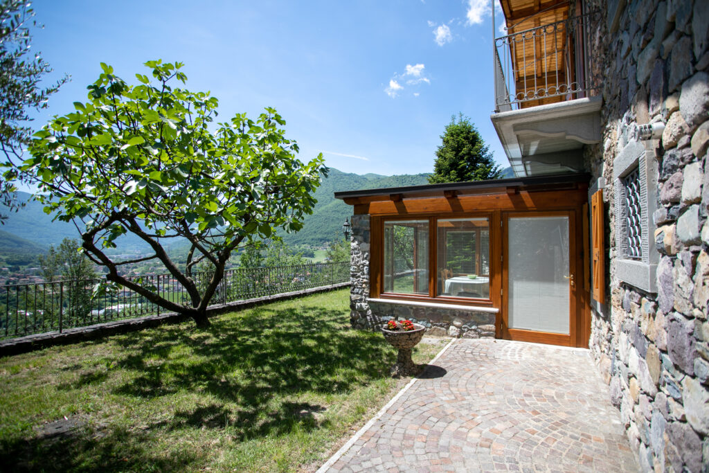 Glass-enclosed veranda at Villa Simone with a view of the lush garden and surrounding mountains