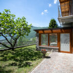 Glass-enclosed veranda at Villa Simone with a view of the lush garden and surrounding mountains