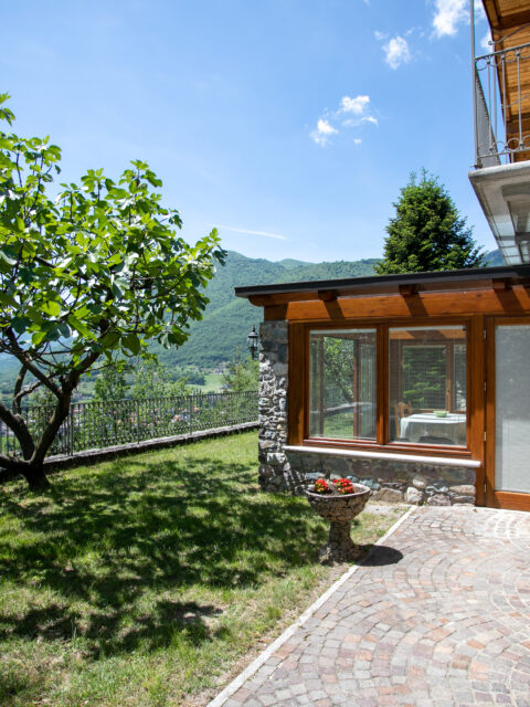 Glass-enclosed veranda at Villa Simone with a view of the lush garden and surrounding mountains