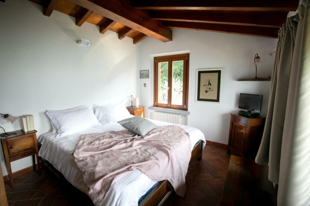 Serene bedroom with open window offering a glimpse of Lake Iseo's natural beauty at La Stallina Penthouse