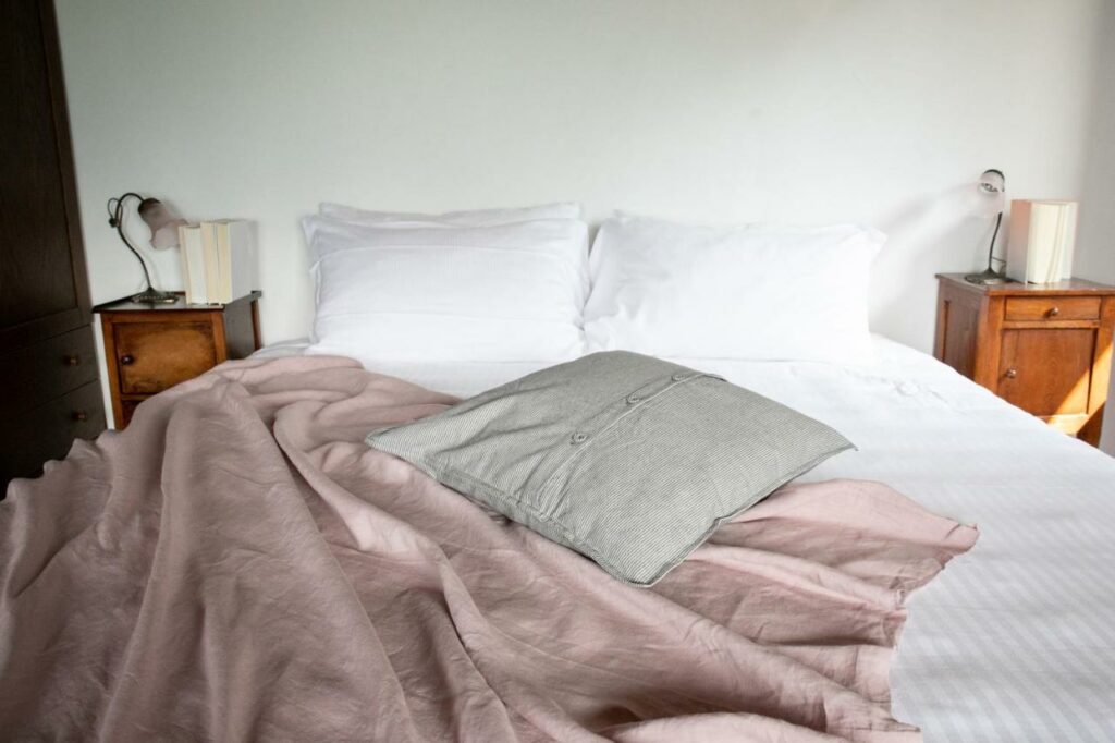 Inviting and serene bedroom with plush white bedding and a vintage bedside table at La Stallina Attico