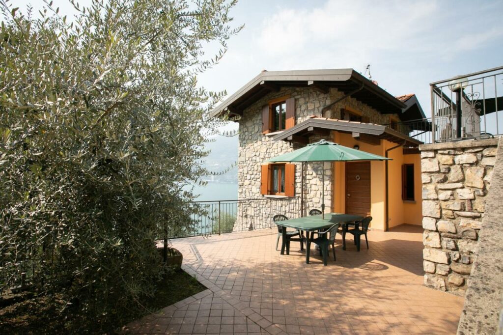 Stone patio with outdoor dining set at La Stallina Penthouse, surrounded by olive trees with lake views