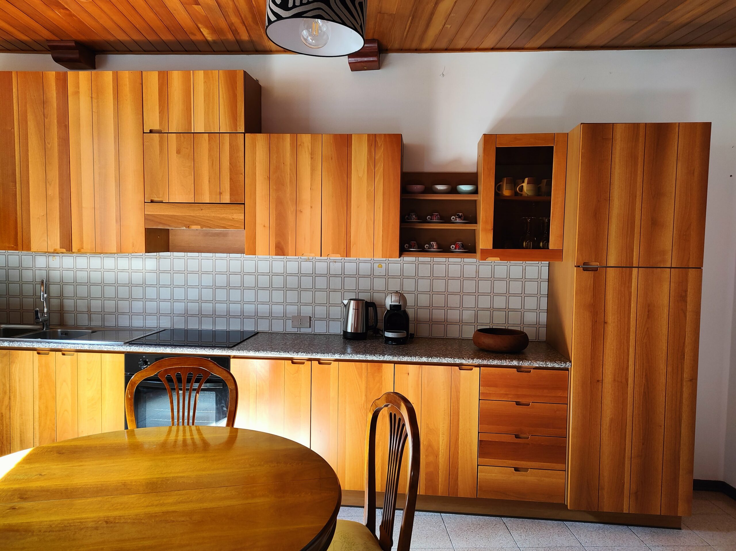 Modern wooden kitchen with dining table and appliances at La Porta Sul Lago by Fabula Home Rental