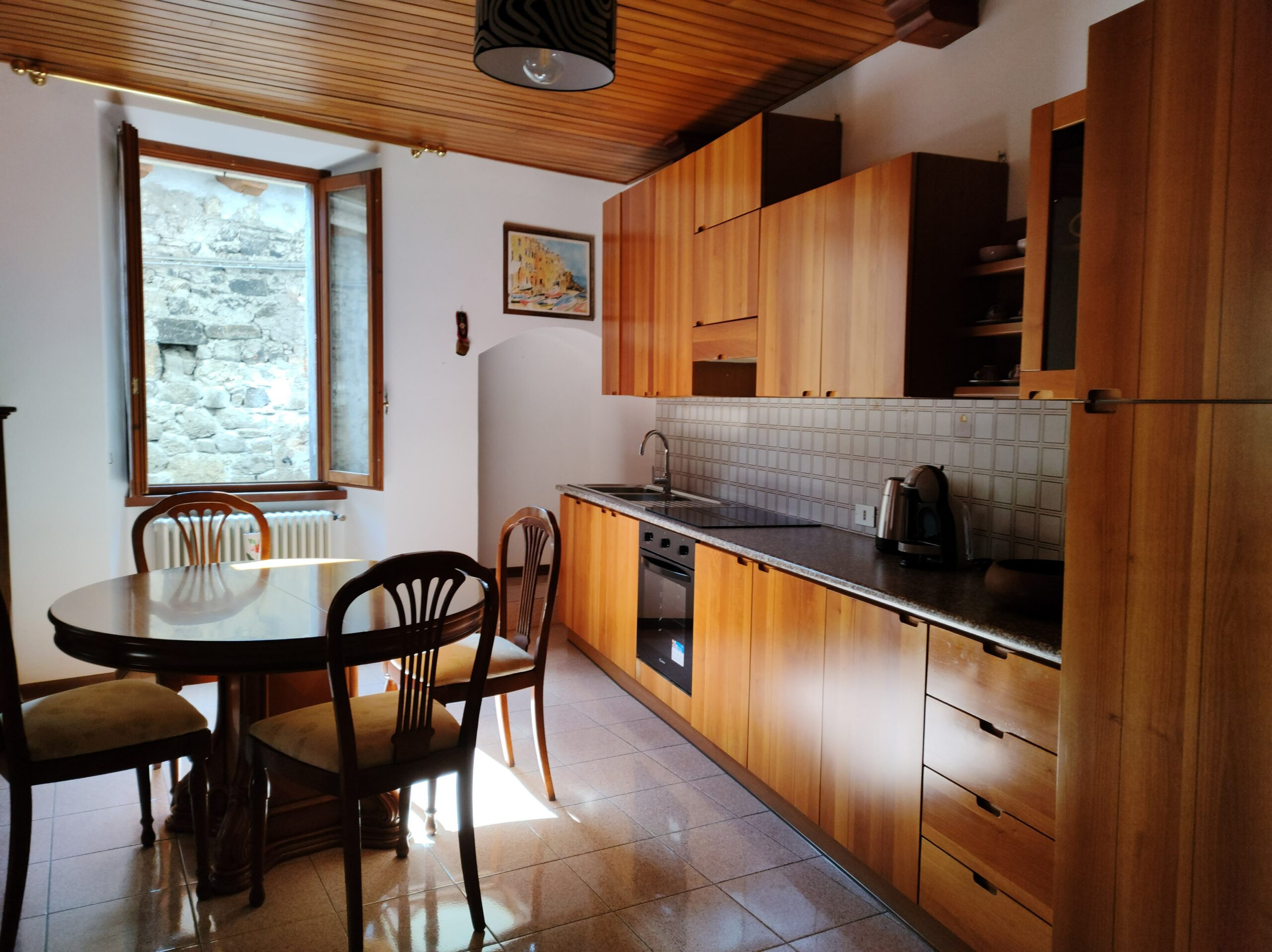 Modern wooden kitchen with dining table and window view at La Porta Sul Lago by Fabula Home Rental