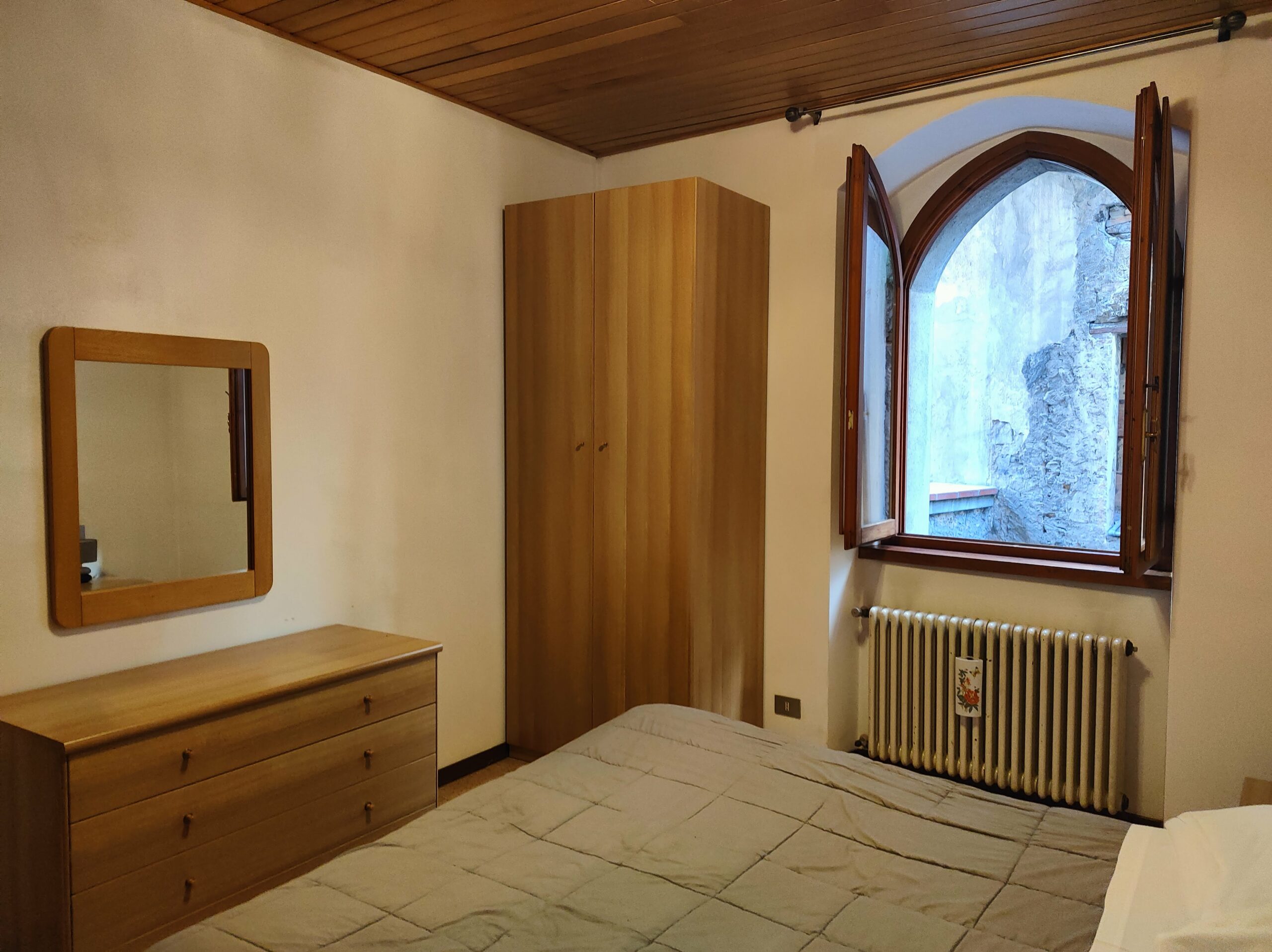 Bedroom with a large bed and view of the courtyard in La Porta Sul Lago apartment