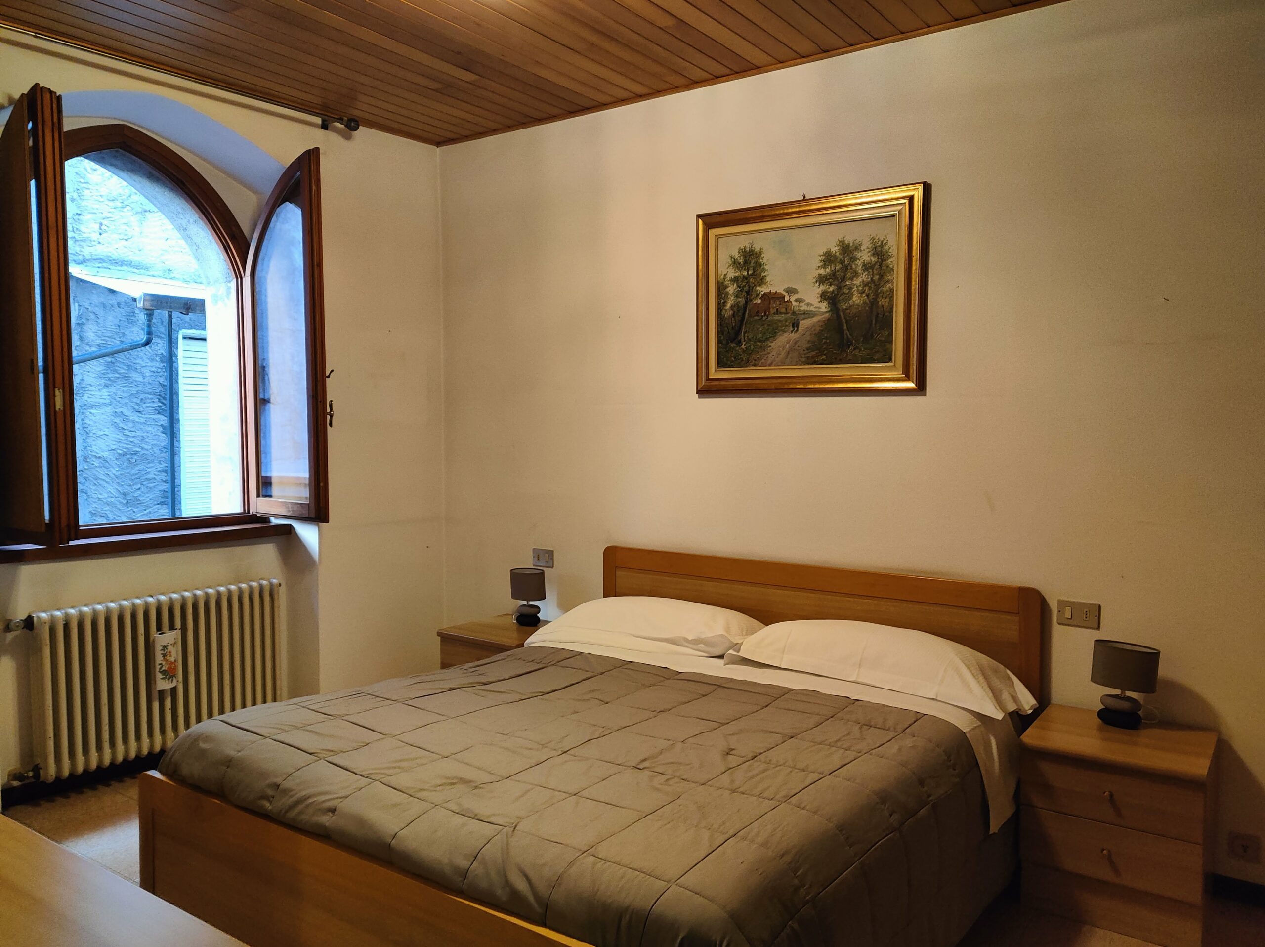 Comfortable bedroom with a large bed and wooden furniture in La Porta Sul Lago apartment