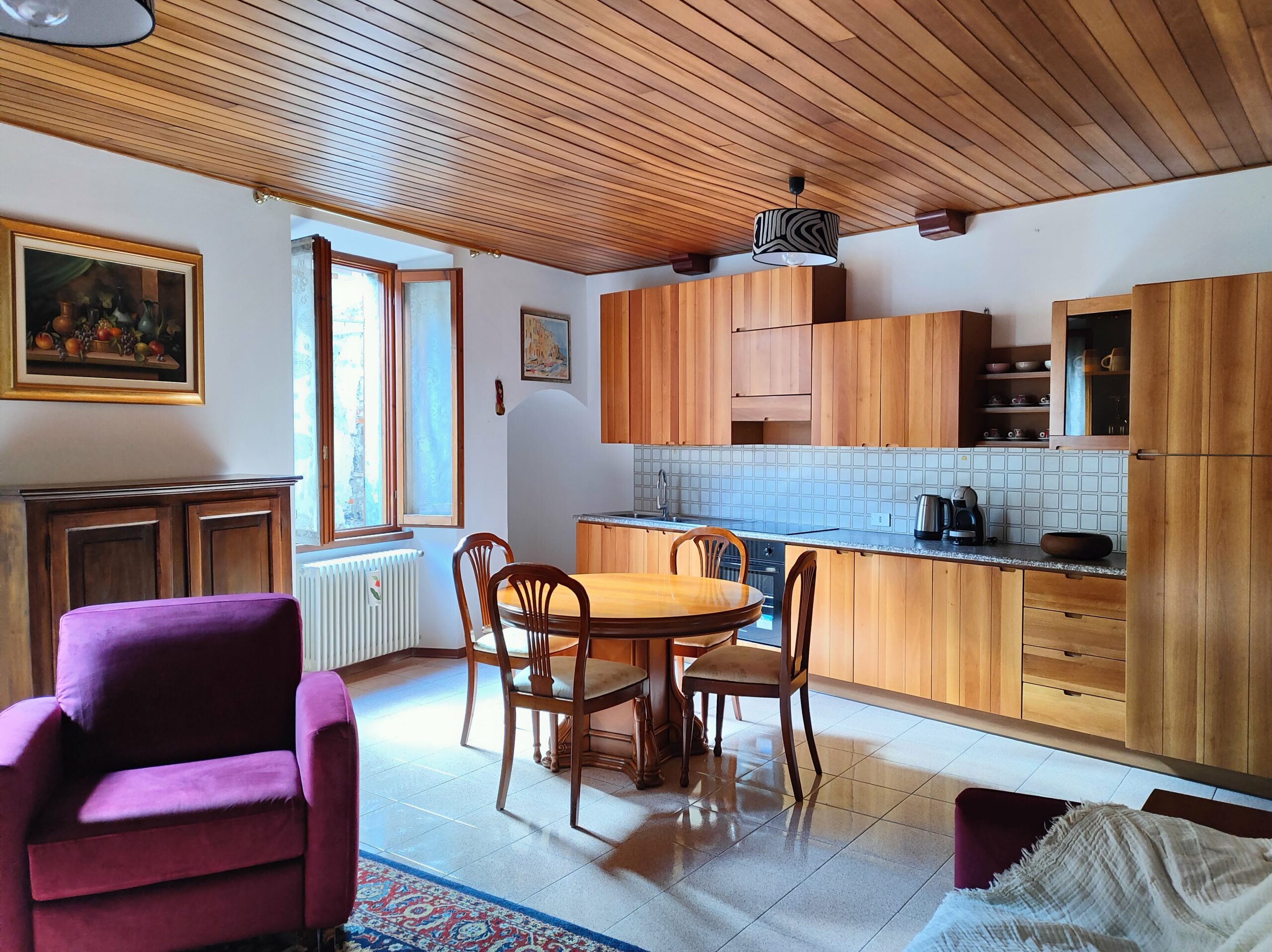 Kitchen and dining area with wooden cabinets in La Porta Sul Lago apartment